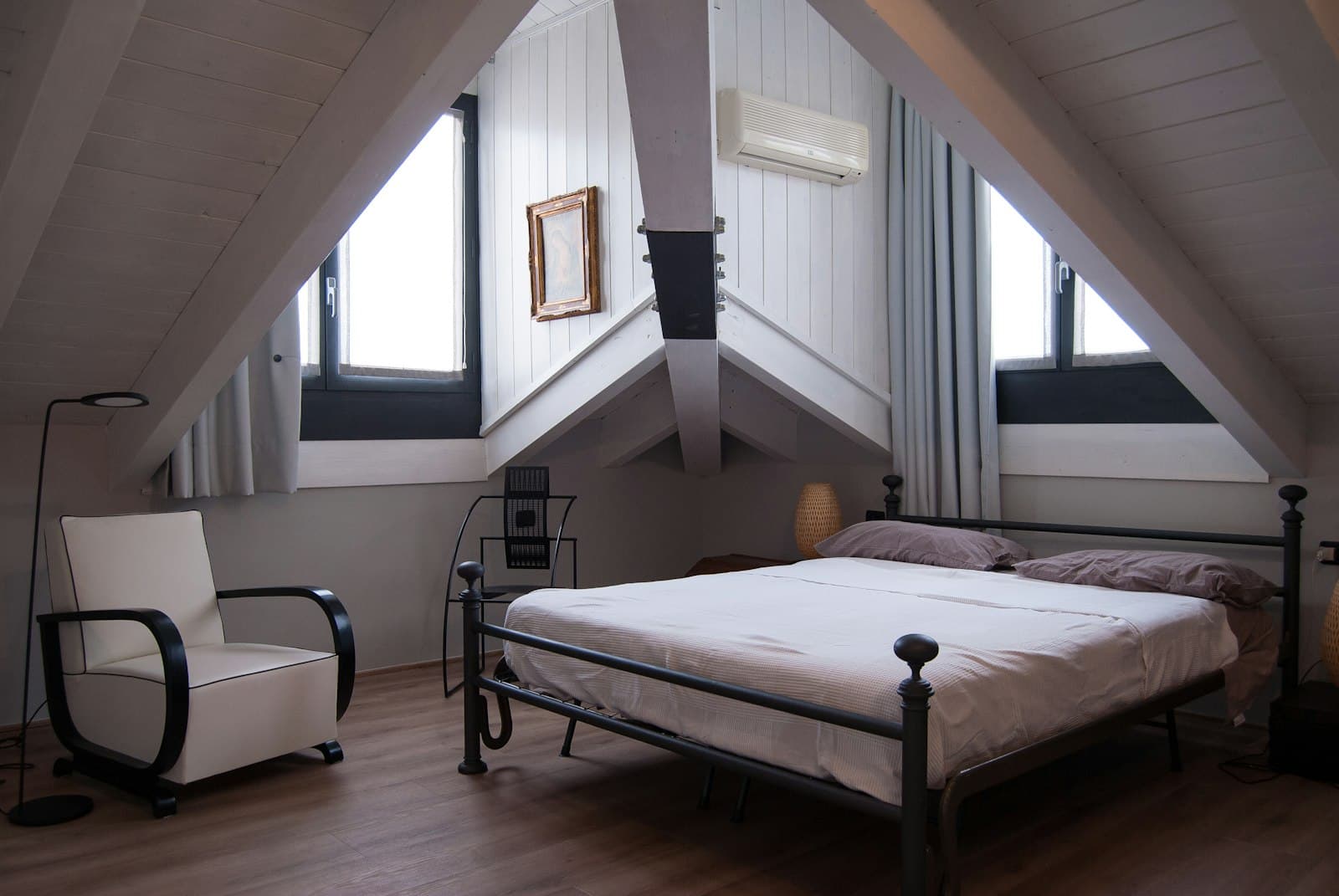 A mattress resting on a black steel bed frame in an attic bedroom
