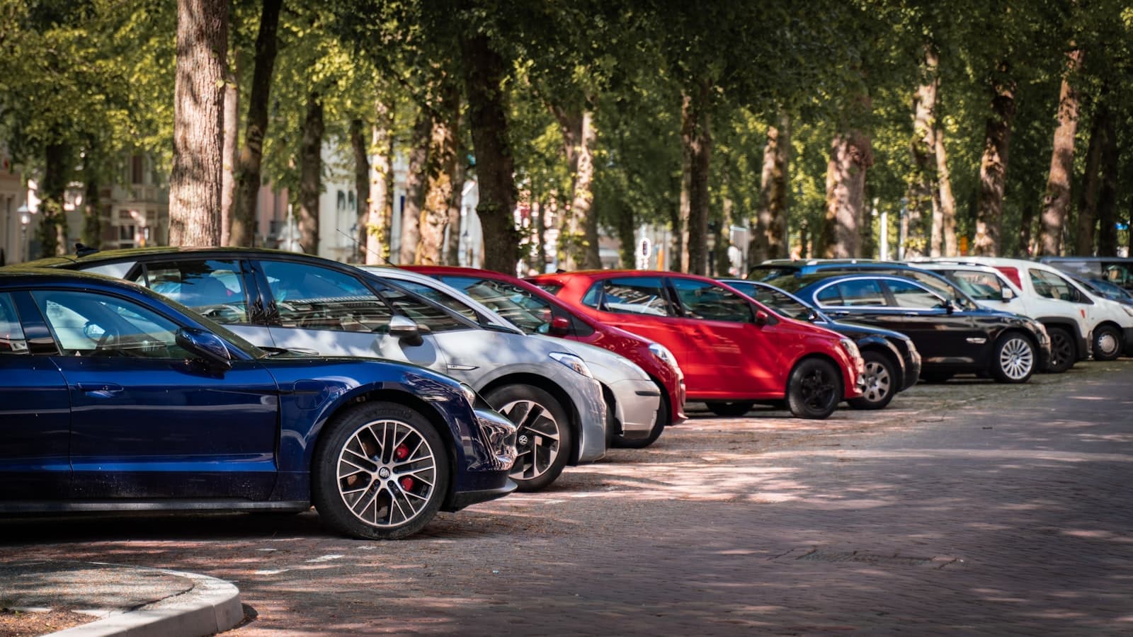 A row of cars parked along a tree-lined street