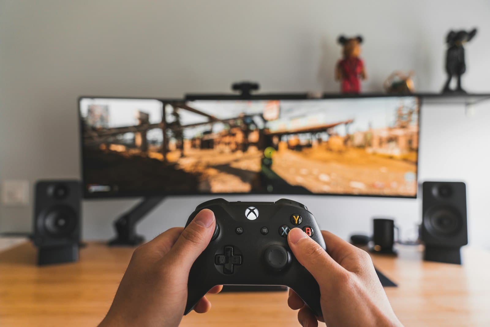 Hands holding a game controller in front of a monitor