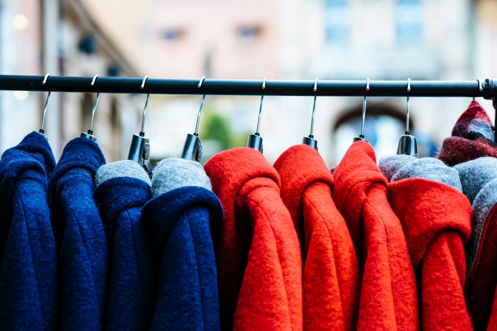 Blue and red wool coats hanging on a clothing rack